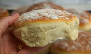 En hand håller ett nybakat tekaka, pudrad med mjöl. Perfekt för ett enkelt tekakor recept.