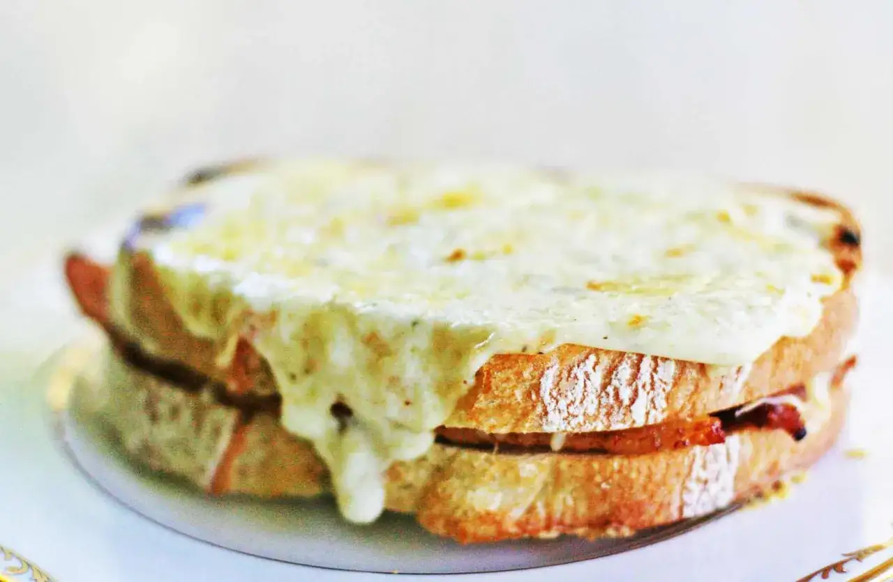 En gyllene, smält ost täcker en saftig croque monsieur, med skivor av rostat bröd och en hemlig fyllning.