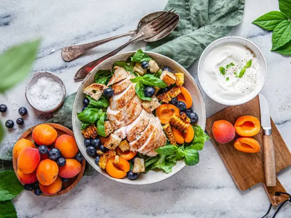 En läcker grillad kyckling sallad med blåbär, aprikoser och krutonger. Serveras med en krämig yoghurtdressing.